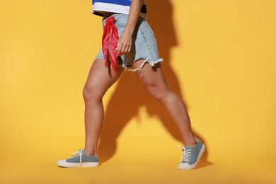 Woman wearing stylish denim shorts on yellow background, closeup