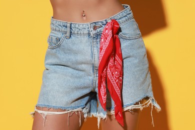 Photo of Woman wearing stylish denim shorts on yellow background, closeup