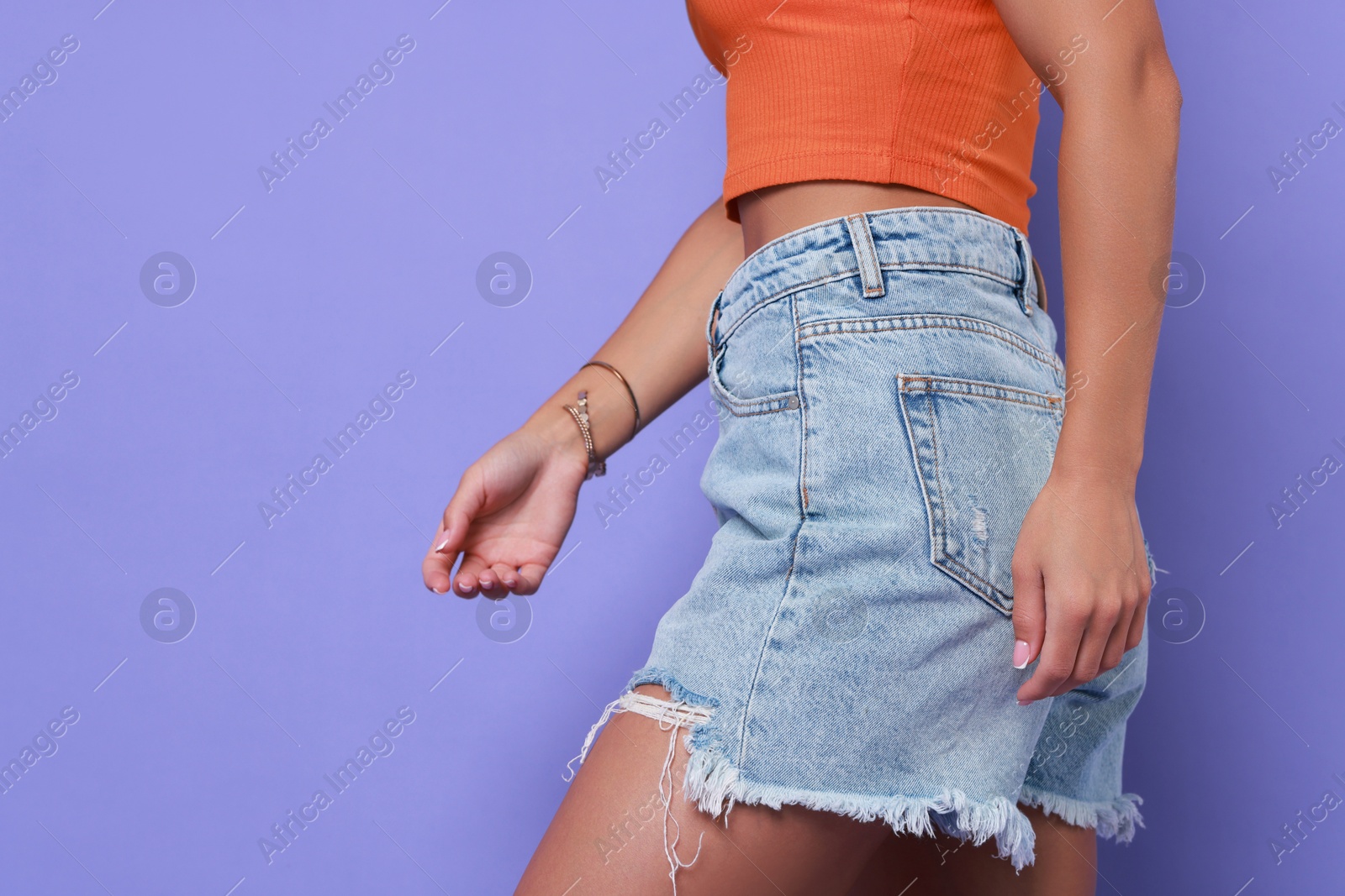 Photo of Woman wearing stylish denim shorts on violet background, closeup