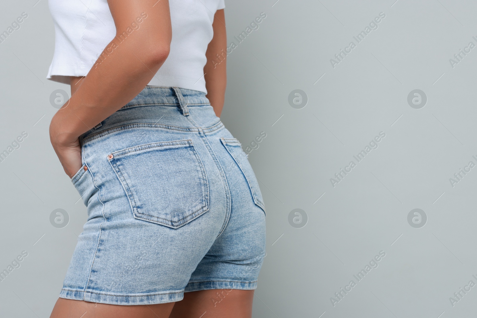 Photo of Woman wearing stylish denim shorts on gray background, closeup. Space for text