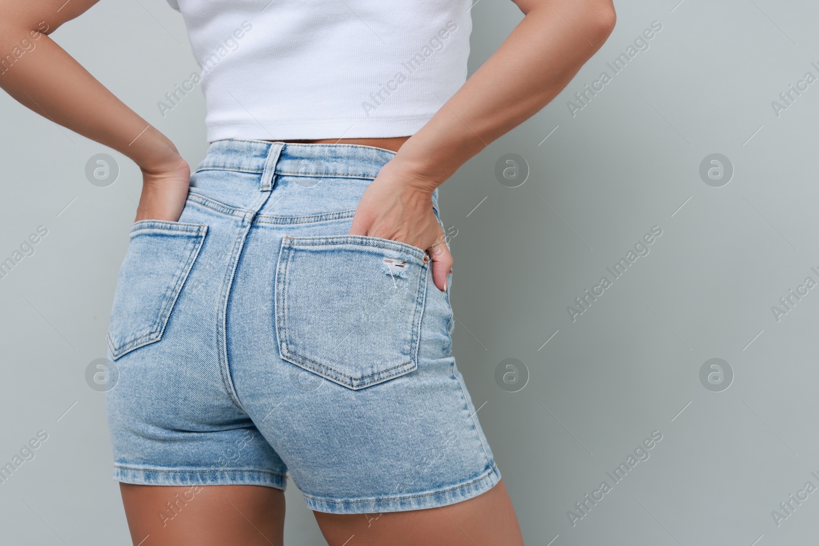 Photo of Woman wearing stylish denim shorts on gray background, closeup. Space for text