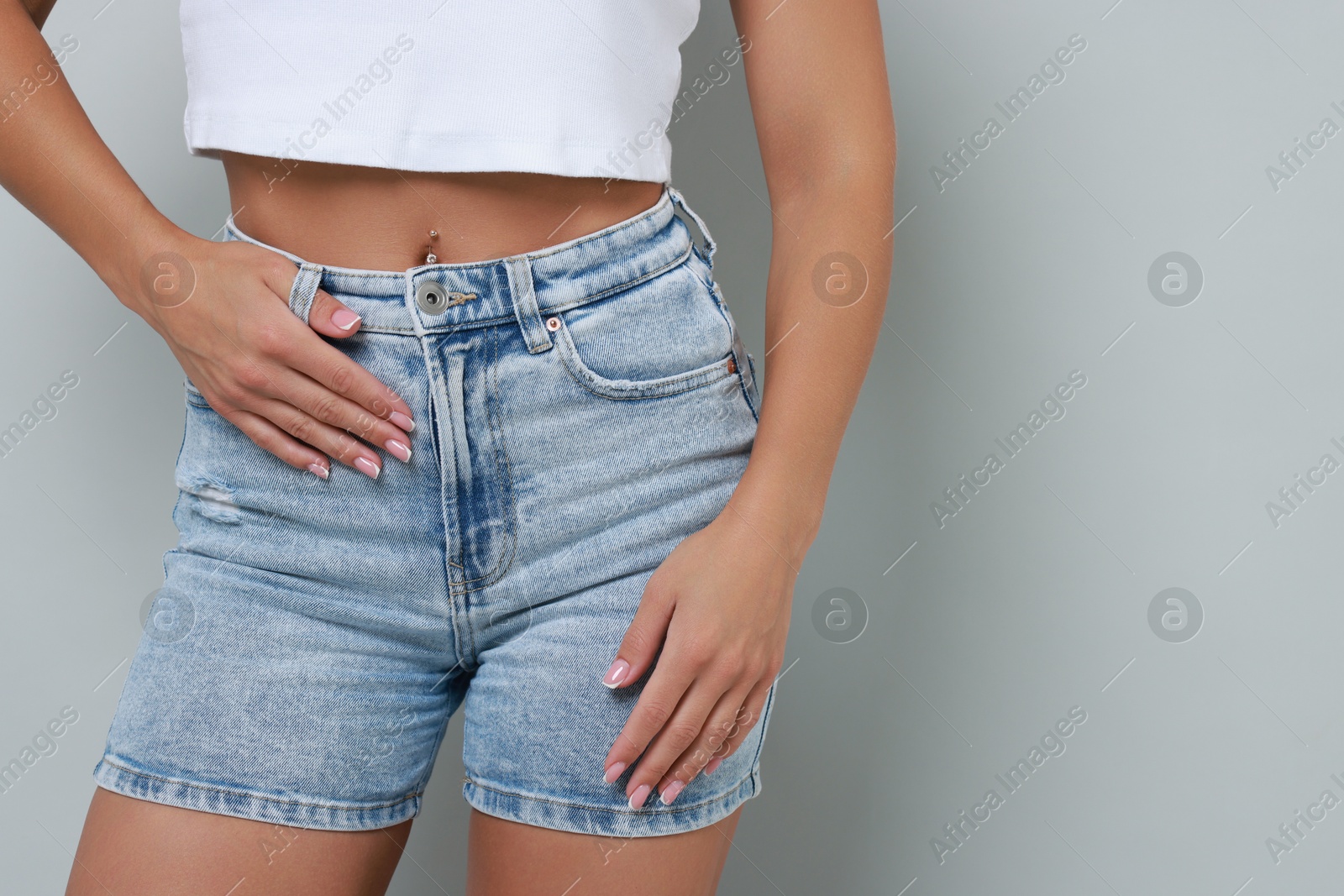 Photo of Woman wearing stylish denim shorts on gray background, closeup. Space for text