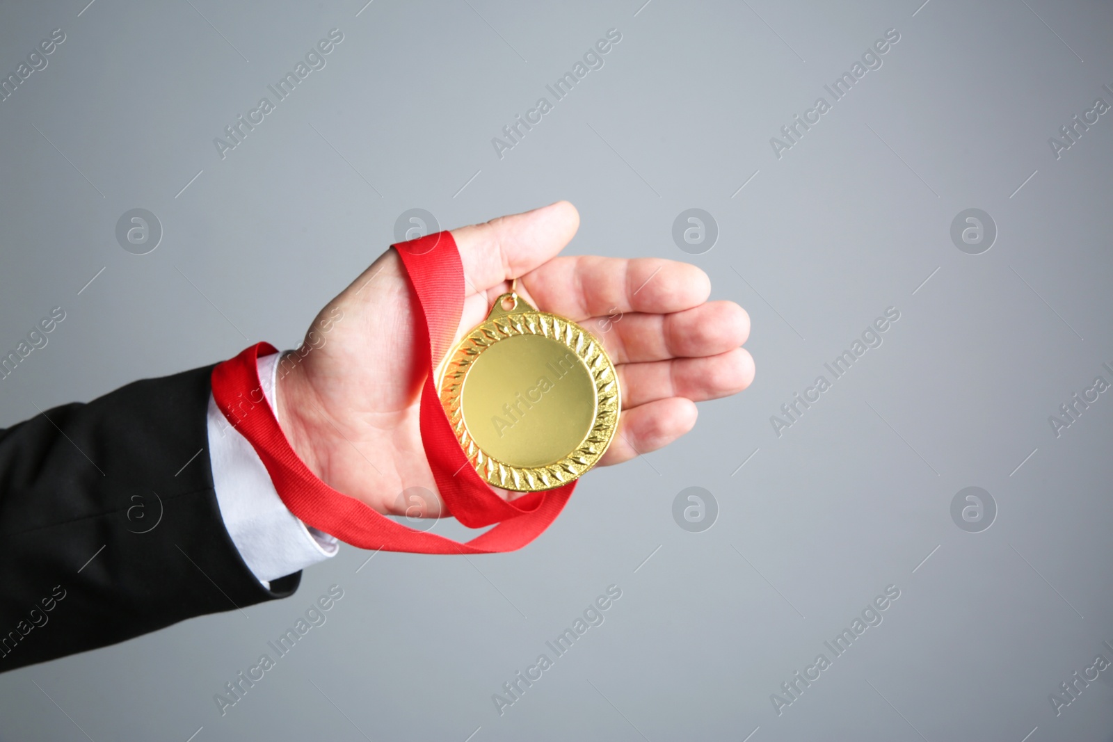 Photo of Man with golden medal on grey background, closeup