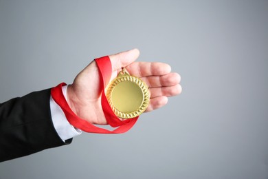 Photo of Man with golden medal on grey background, closeup