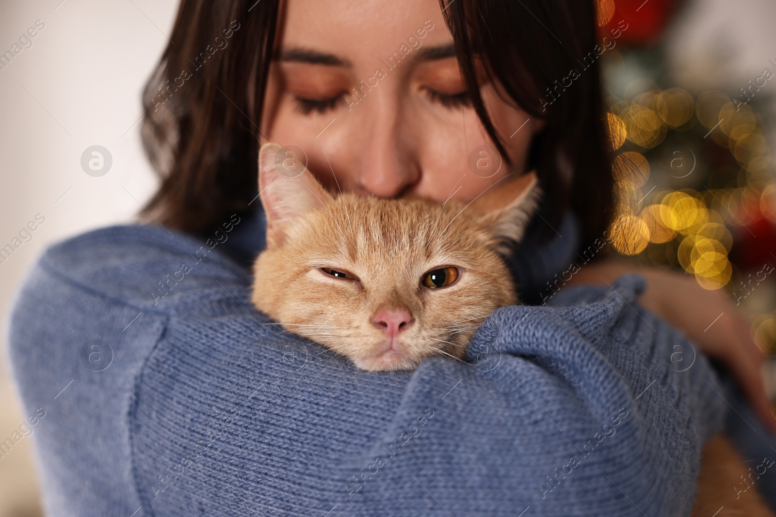 Photo of Woman with cute ginger cat in room decorated for Christmas, closeup