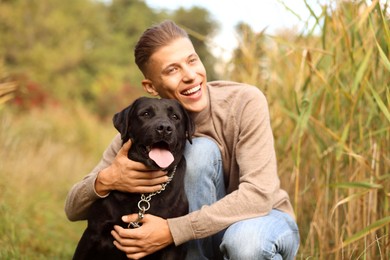 Photo of Smiling man with cute dog outdoors on autumn day