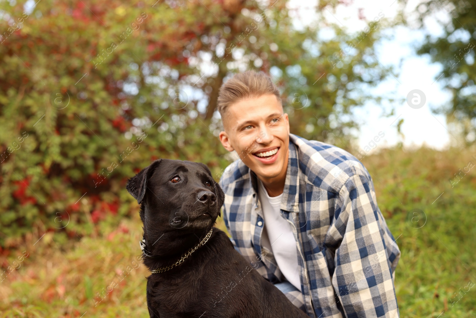 Photo of Smiling man with cute dog outdoors on autumn day