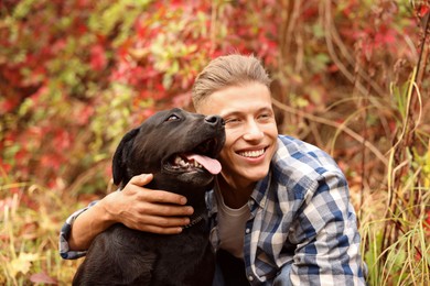 Photo of Smiling man with cute dog outdoors on autumn day