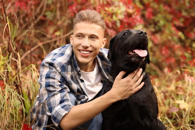 Photo of Smiling man with cute dog outdoors on autumn day