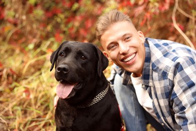 Photo of Smiling man with cute dog outdoors on autumn day