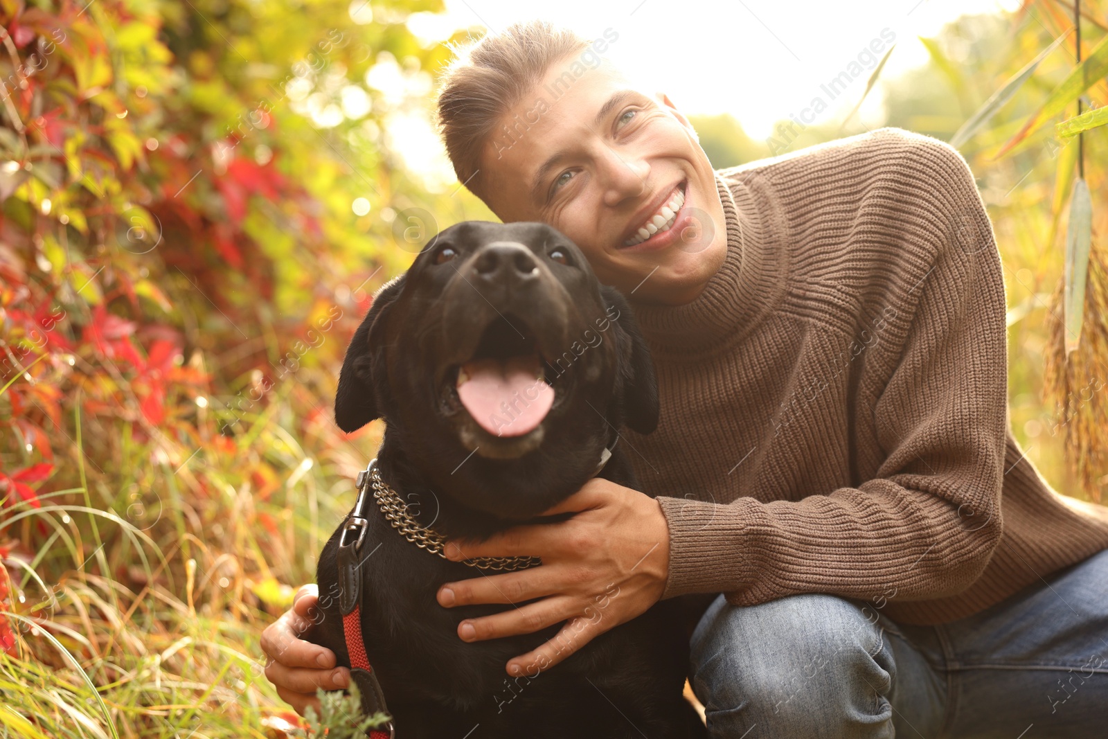 Photo of Smiling man with cute dog outdoors on autumn day