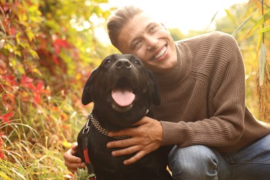 Smiling man with cute dog outdoors on autumn day