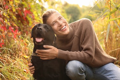 Photo of Smiling man with cute dog outdoors on autumn day