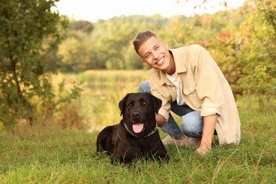 Photo of Smiling man with cute dog outdoors on autumn day. Space for text