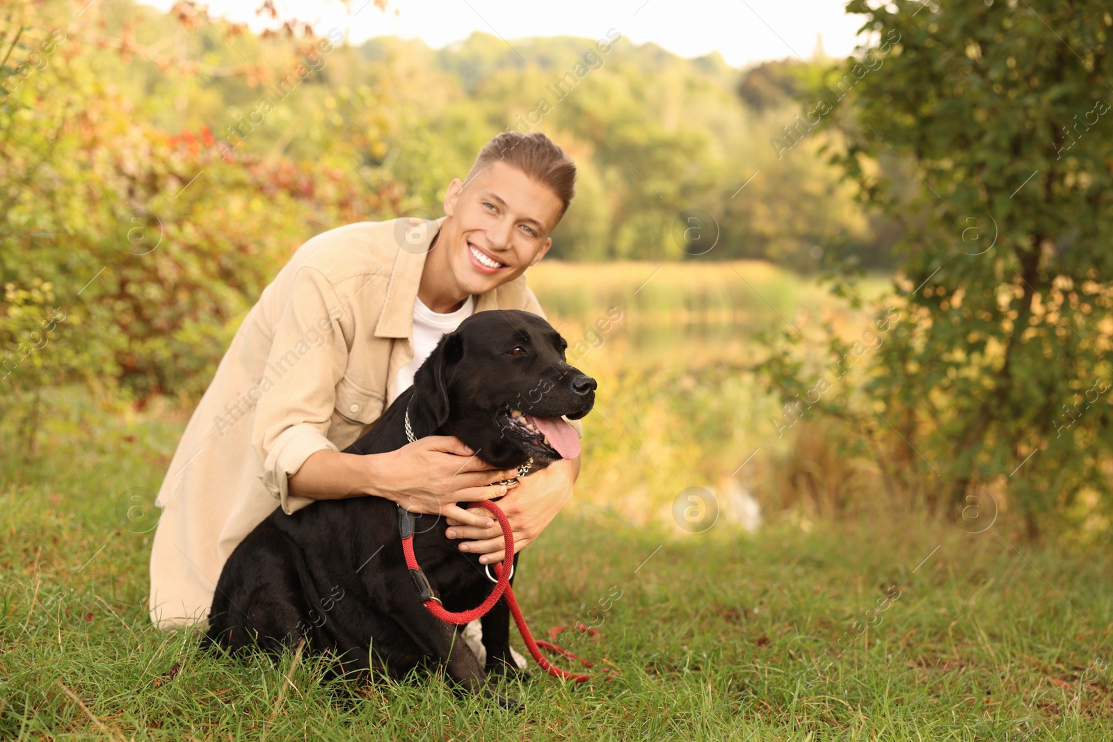 Photo of Smiling man with cute dog outdoors on autumn day. Space for text