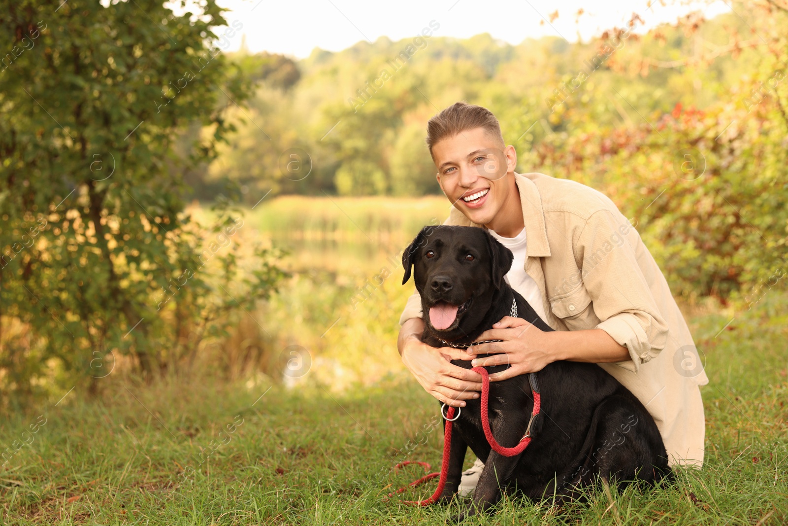 Photo of Smiling man with cute dog outdoors on autumn day. Space for text