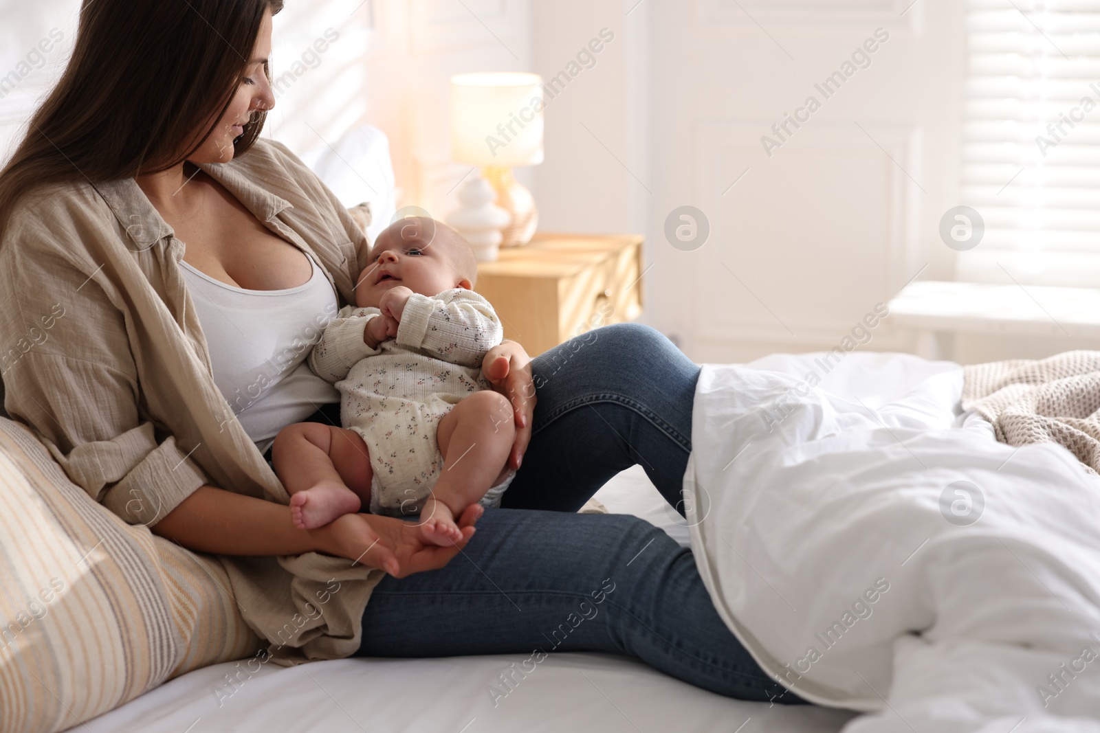 Photo of Mother with her cute little baby on bed at home