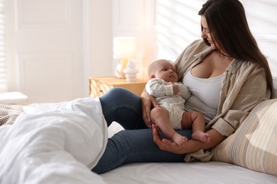 Mother with her cute little baby on bed at home