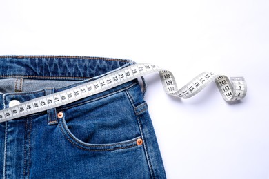 Photo of Jeans and measuring tape on white background, top view