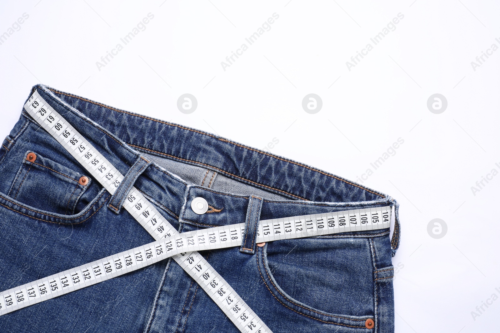 Photo of Jeans and measuring tape on white background, top view