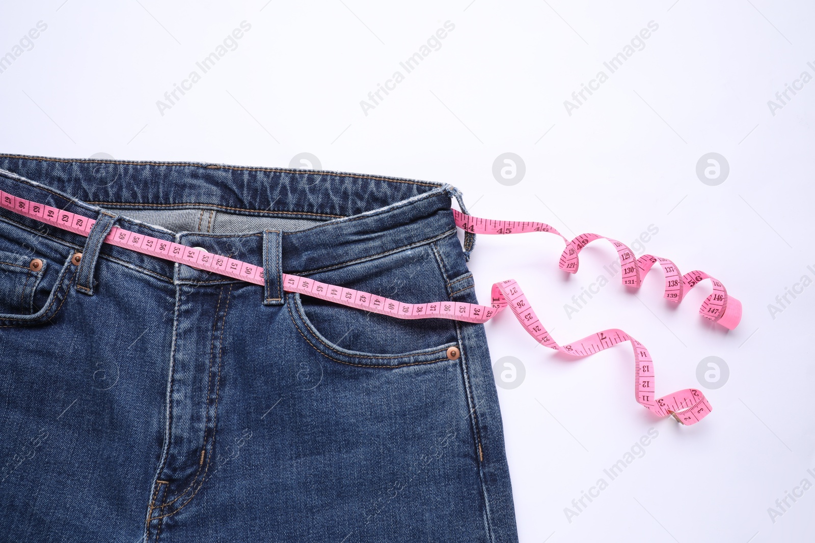 Photo of Jeans and measuring tape on white background, top view