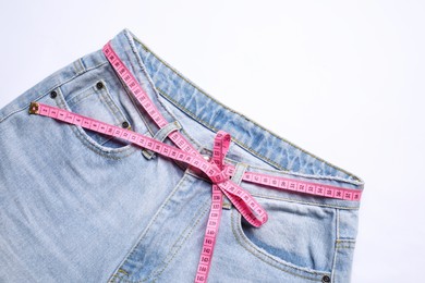 Photo of Jeans and measuring tape on white background, top view