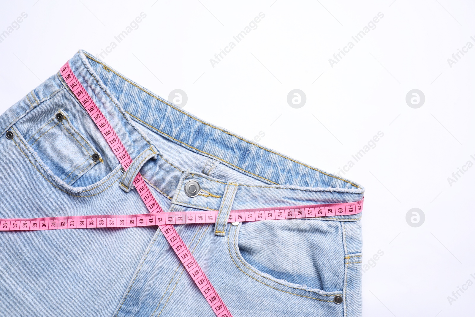 Photo of Jeans and measuring tape on white background, top view