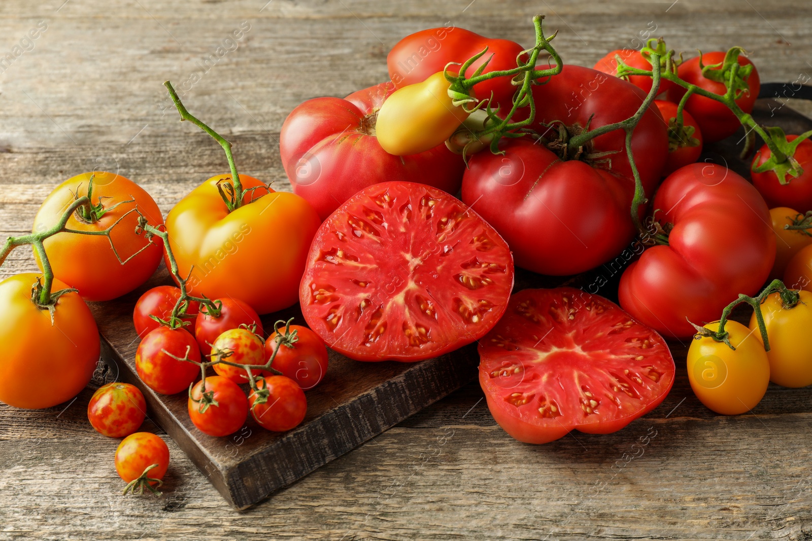 Photo of Many different ripe tomatoes on wooden table