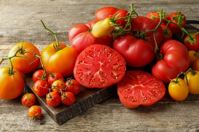 Photo of Many different ripe tomatoes on wooden table