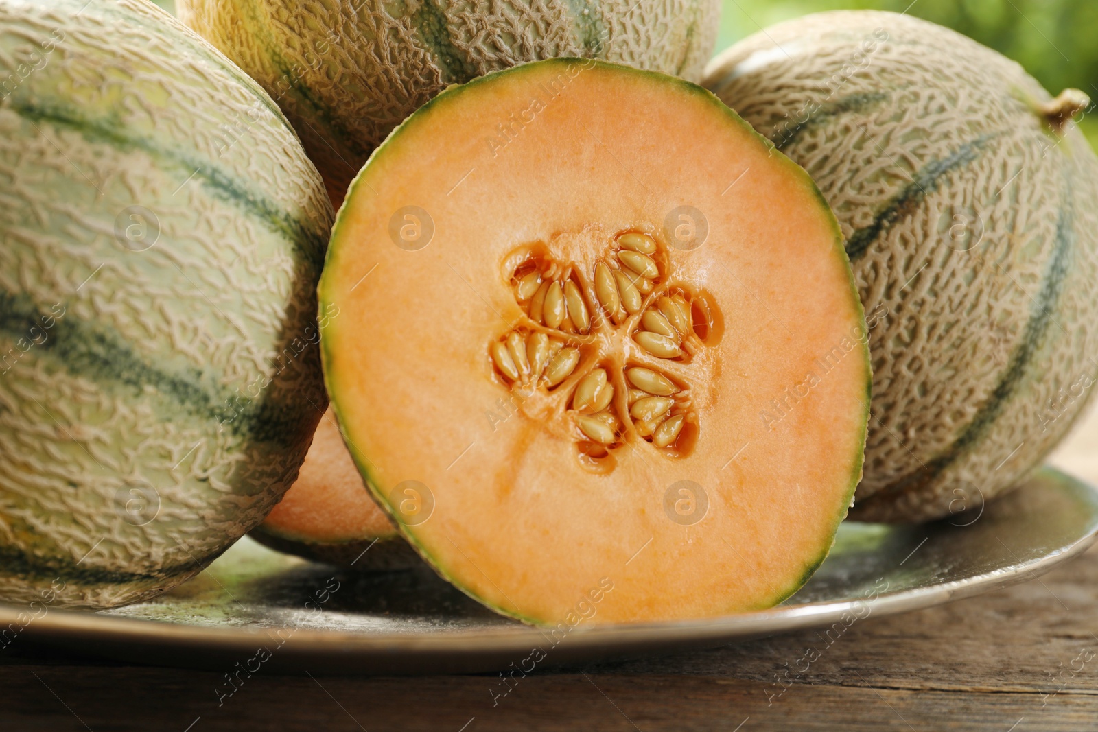 Photo of Whole and cut ripe Cantaloupe melons on wooden table, closeup