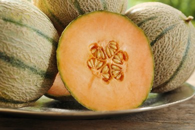 Whole and cut ripe Cantaloupe melons on wooden table, closeup