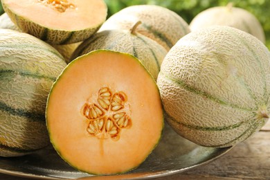 Whole and cut ripe Cantaloupe melons on wooden table, closeup