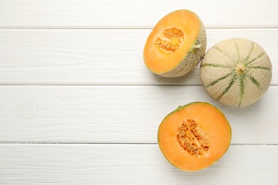 Photo of Whole and cut ripe Cantaloupe melons on white wooden table, flat lay. Space for text