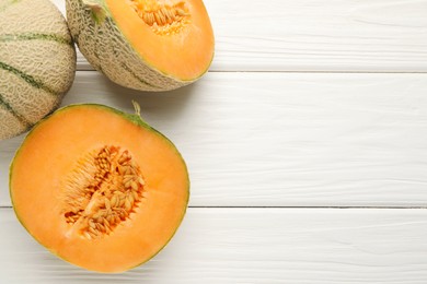 Photo of Whole and cut ripe Cantaloupe melons on white wooden table, flat lay. Space for text