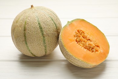 Photo of Whole and cut ripe Cantaloupe melons on white wooden table, closeup