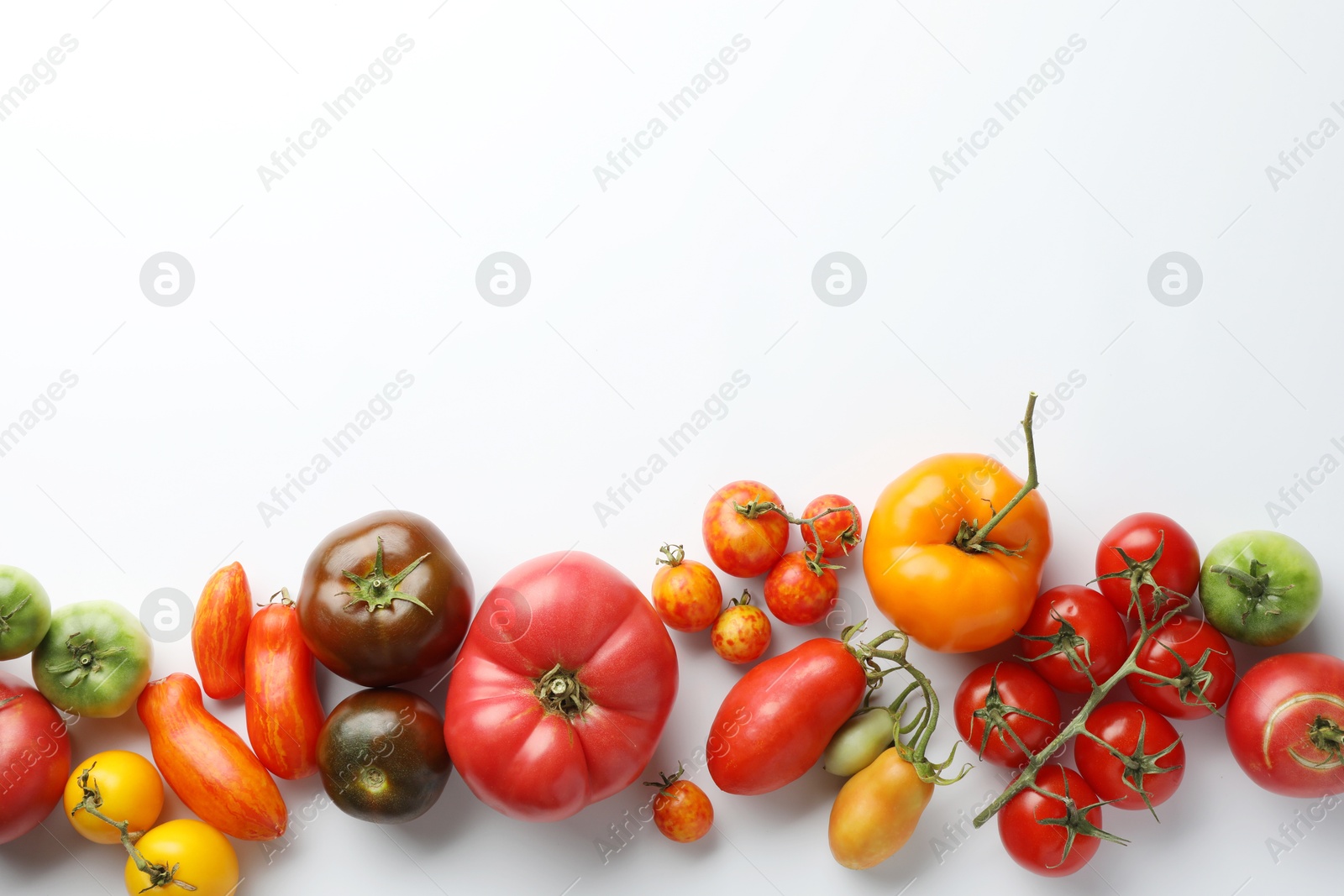 Photo of Different ripe tomatoes on white background, top view. Space for text