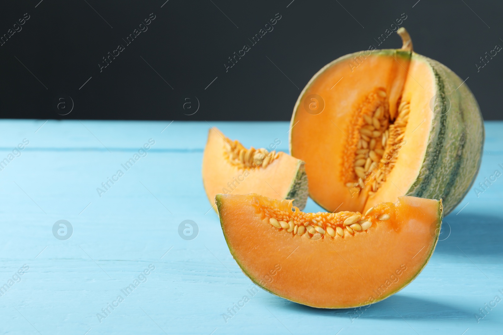 Photo of Cut ripe Cantaloupe melon on light blue wooden table, closeup. Space for text