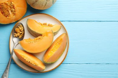 Photo of Cut ripe Cantaloupe melon and spoon with seeds on light blue wooden table, flat lay. Space for text