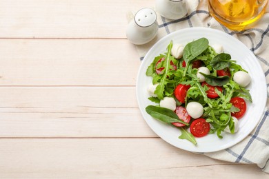 Photo of Tasty salad with arugula, spinach, mozzarella cheese and tomatoes on wooden table, flat lay. Space for text