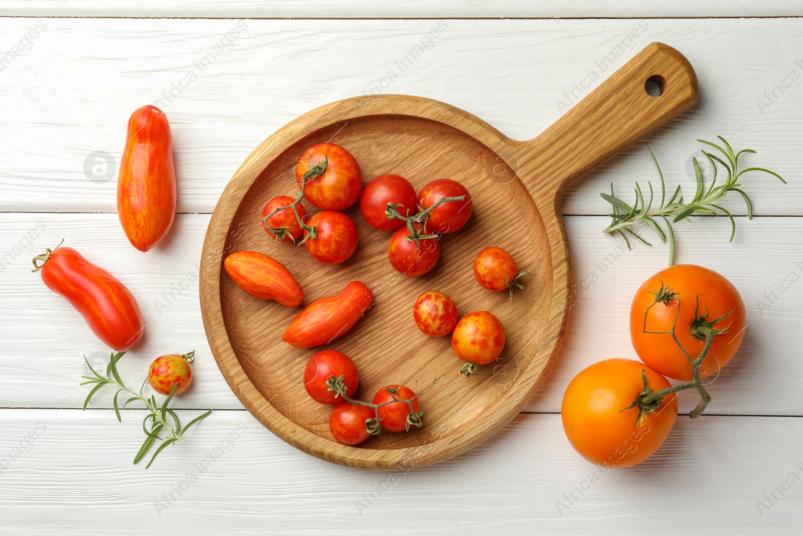 Photo of Different ripe tomatoes and rosemary on white wooden table, flat lay