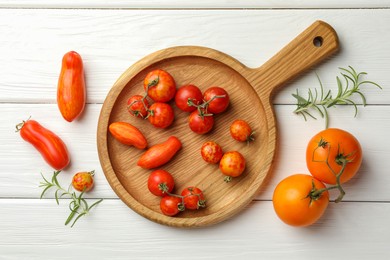 Photo of Different ripe tomatoes and rosemary on white wooden table, flat lay