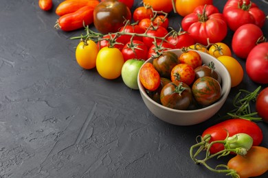 Different fresh tomatoes on grey textured table. Space for text