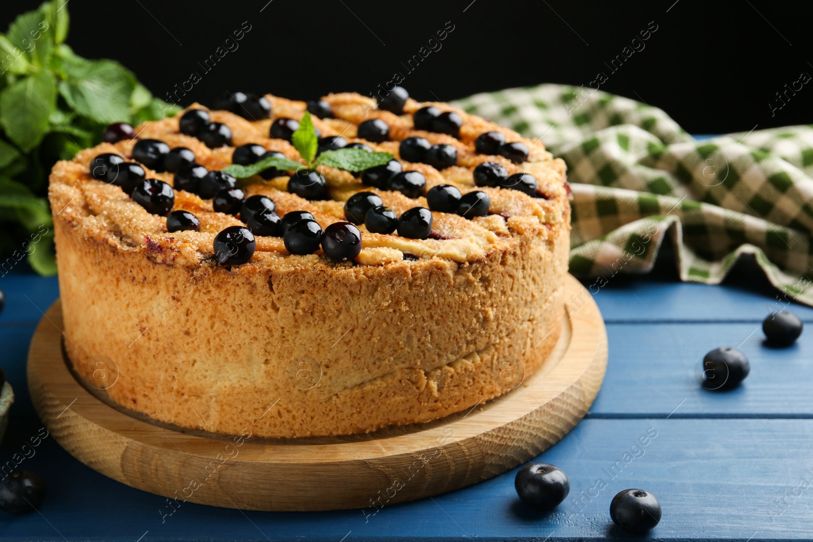 Photo of Delicious homemade blueberry pie with mint and fresh berries on blue wooden table, closeup