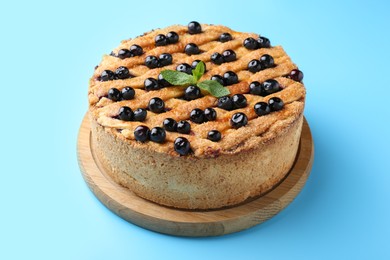 Photo of Delicious homemade blueberry pie with mint on light blue background