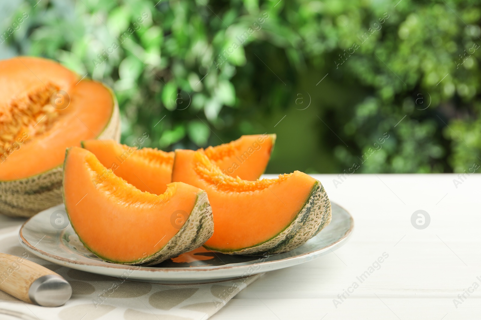 Photo of Pieces of fresh Cantaloupe melon on white wooden table, closeup