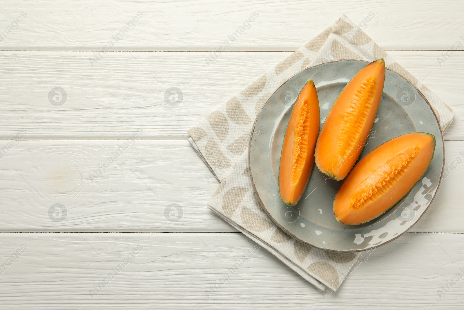 Photo of Pieces of fresh Cantaloupe melon on white wooden table, top view. Space for text