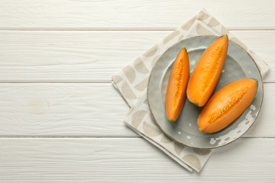 Photo of Pieces of fresh Cantaloupe melon on white wooden table, top view. Space for text