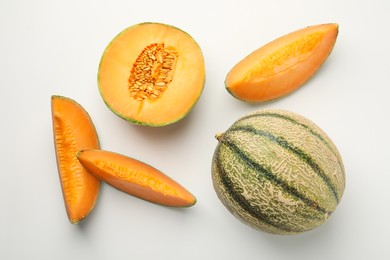 Photo of Cut and whole Cantaloupe melons on white table, flat lay