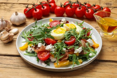 Photo of Tasty salad with arugula, egg, cheese and vegetables on wooden table, closeup