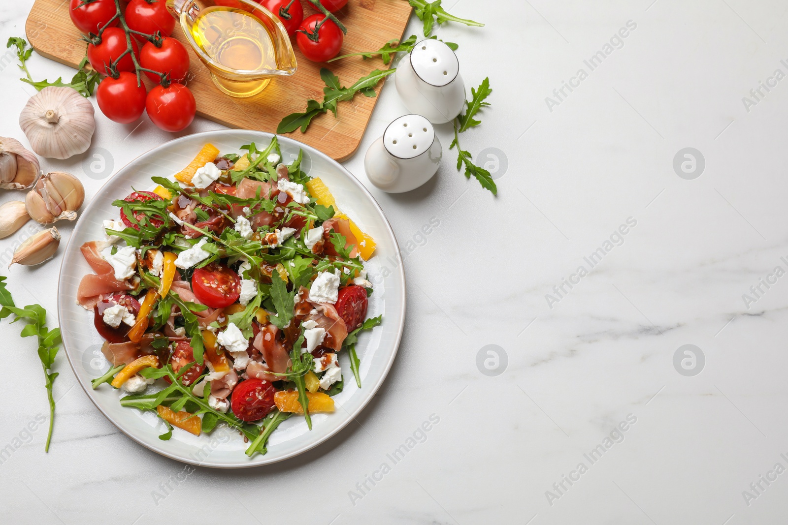 Photo of Tasty salad with arugula, cheese and vegetables on white marble table, flat lay. Space for text